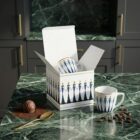 Espresso cup “Stay together Blue”, limited edition designer espresso cup with artistic illustration by NONOS, stylish porcelain cup with saucer, coffee being poured, close-up view.