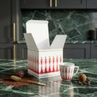 Espresso-Tasse „Stay Together – Rot“, limitierte Designer-Espressotasse mit stilisierter Figurenillustration von NONOS, hochwertige Porzellantasse mit Untertasse, Kaffee wird eingeschenkt, Detailaufnahme.