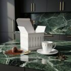 Espresso-Tasse „Stay Together – Weiss“, limitierte Designer-Espressotasse mit stilisierter Figurenillustration von NONOS, hochwertige Porzellantasse mit Untertasse, Kaffee wird eingeschenkt, Detailaufnahme.