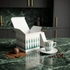 Espresso cup “Stay Together – Green”, limited edition designer espresso cup with stylized figurative illustration by NONOS, high-quality porcelain cup with saucer, coffee being poured, close-up view.